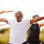 Group Of Mature Men And Women In Class At Outdoor Yoga Retreat